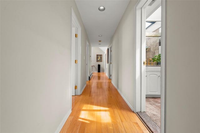 hall with light wood finished floors, recessed lighting, and baseboards