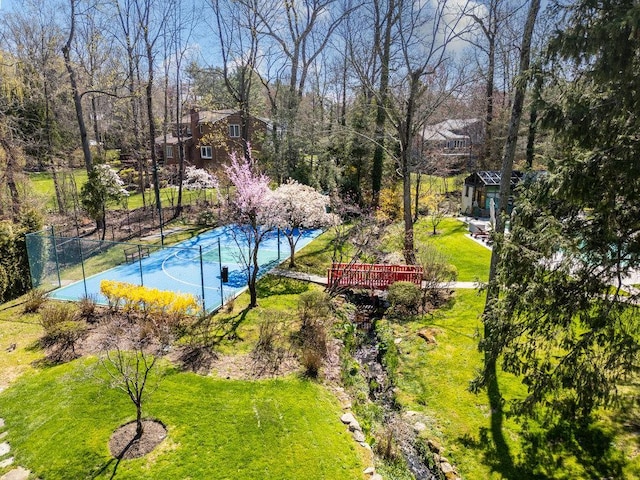 exterior space featuring fence, basketball hoop, and a yard