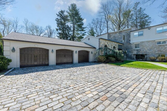 exterior space featuring a front yard, stucco siding, decorative driveway, and an attached garage