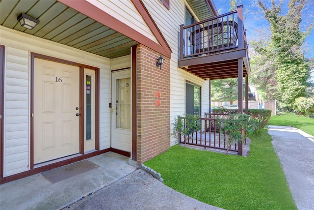 entrance to property featuring brick siding, a balcony, and covered porch