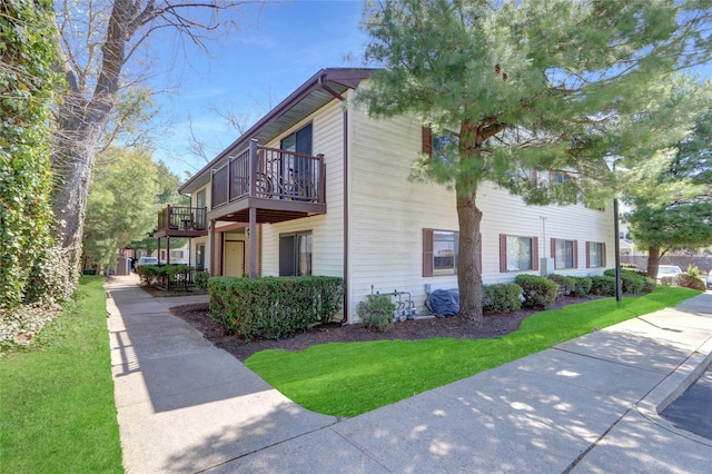 view of home's exterior with a lawn and a balcony