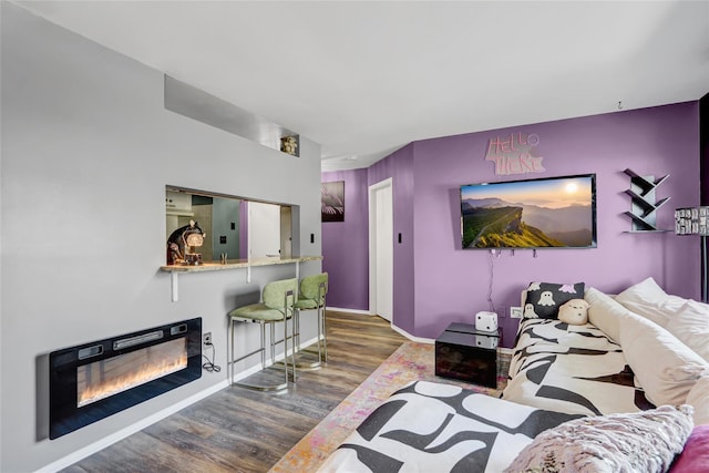 living area featuring a glass covered fireplace, baseboards, and wood finished floors