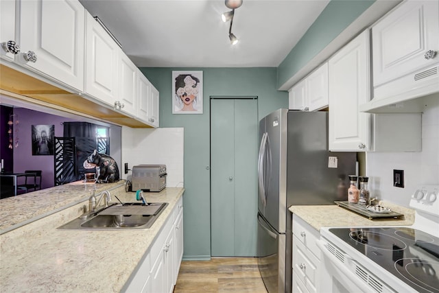 kitchen featuring white electric range oven, a sink, light countertops, light wood-style flooring, and white cabinetry
