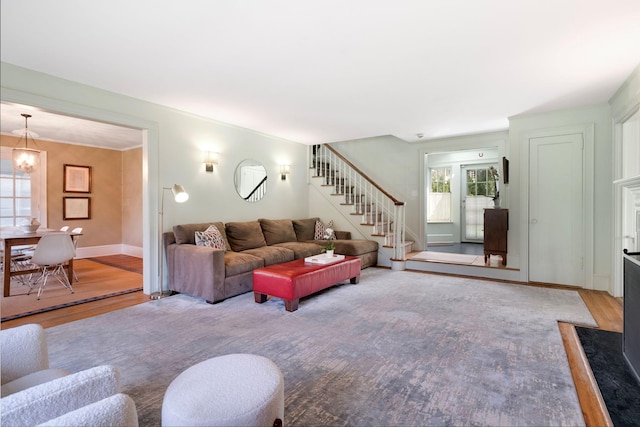 living room featuring stairs, baseboards, a chandelier, and wood finished floors
