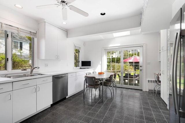 kitchen with a sink, appliances with stainless steel finishes, a wealth of natural light, and radiator