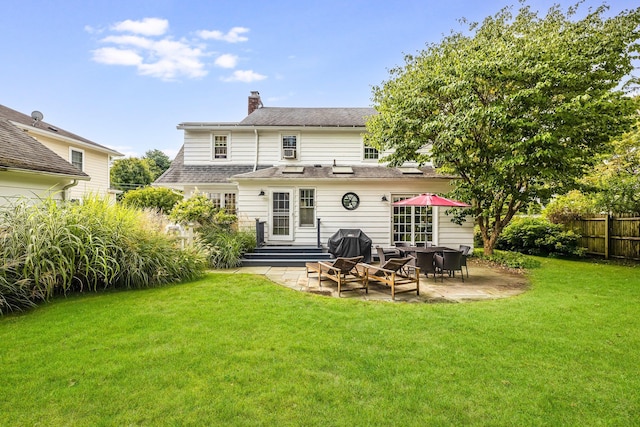 back of property with fence, entry steps, a chimney, a patio area, and a lawn
