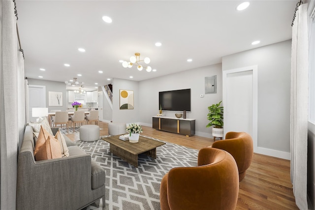living area featuring electric panel, baseboards, wood finished floors, and an inviting chandelier