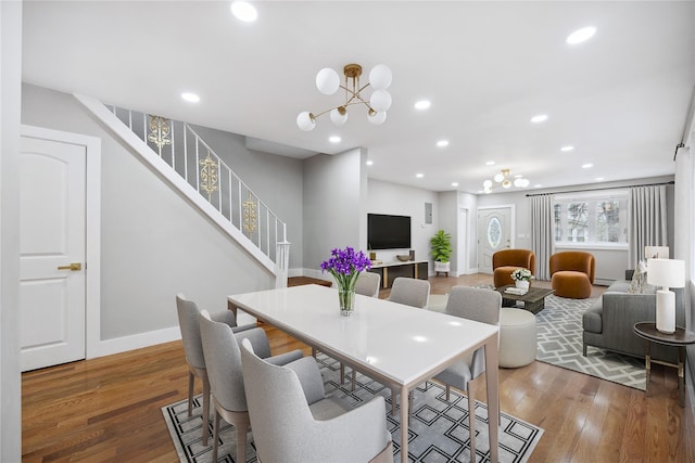 dining space with wood finished floors, an inviting chandelier, and stairs