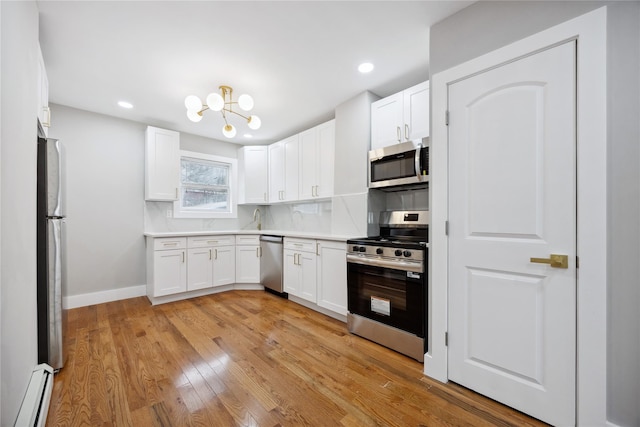 kitchen with baseboard heating, white cabinetry, stainless steel appliances, and light wood finished floors