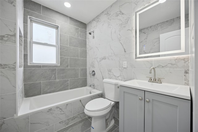 bathroom featuring tile walls, tiled shower / bath combo, toilet, and vanity