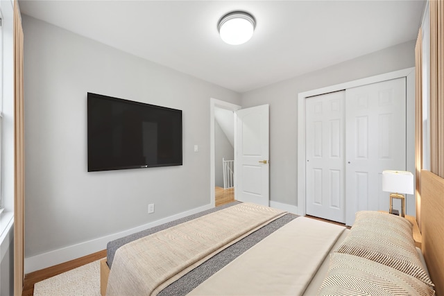 bedroom featuring baseboards, wood finished floors, and a closet