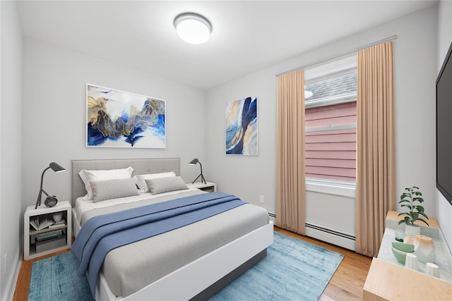 bedroom featuring wood finished floors and a baseboard heating unit