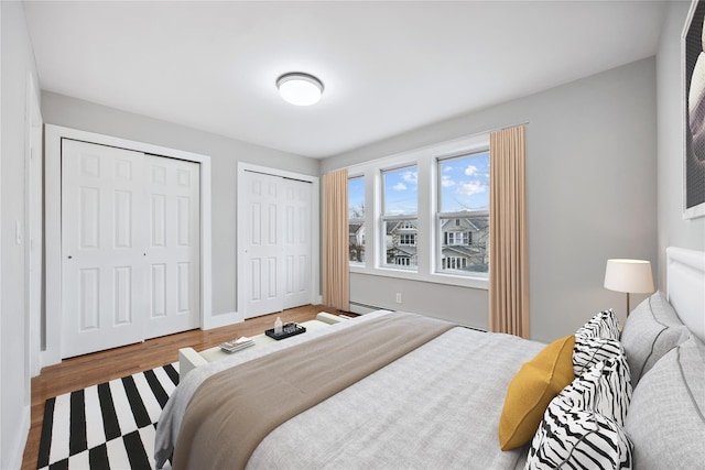 bedroom with wood finished floors and two closets