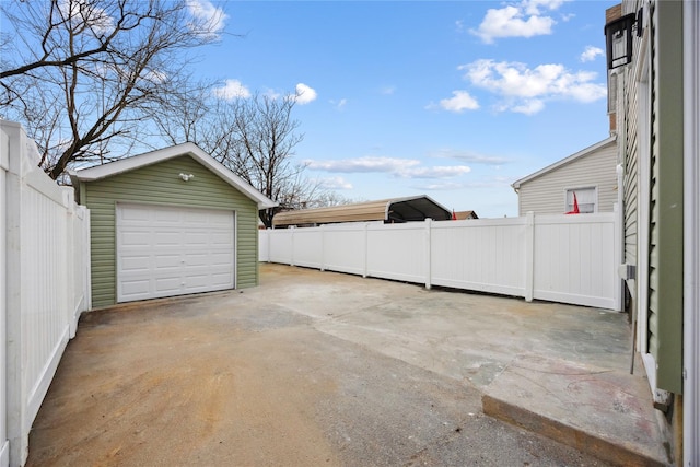 detached garage with fence and concrete driveway