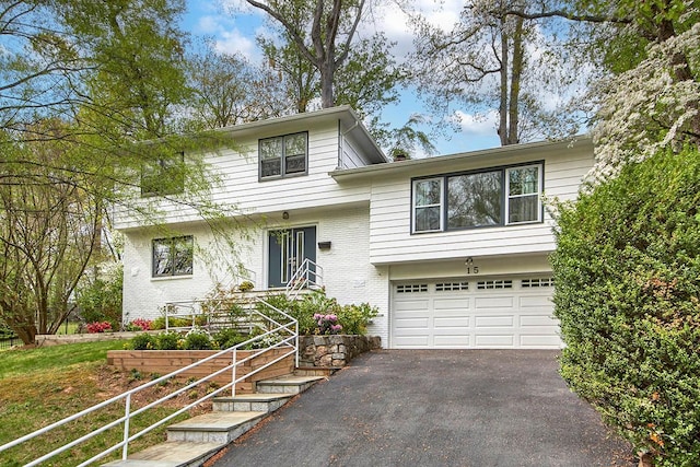 tri-level home with a garage, driveway, and brick siding