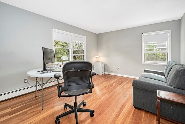 home office featuring a healthy amount of sunlight, baseboards, a baseboard radiator, and light wood finished floors
