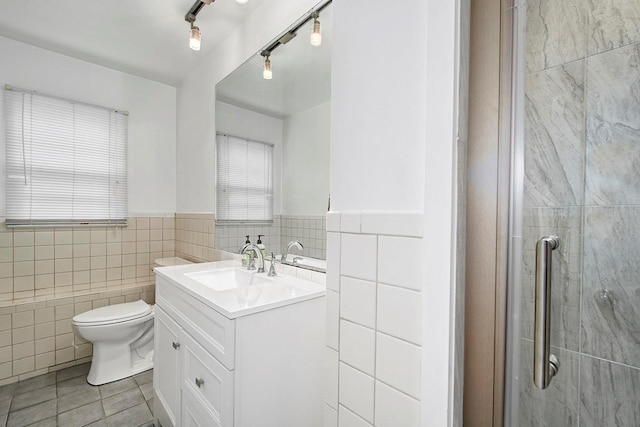 bathroom featuring tile walls, a shower stall, vanity, tile patterned floors, and toilet