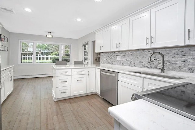 kitchen featuring baseboard heating, a sink, dishwasher, light countertops, and a peninsula