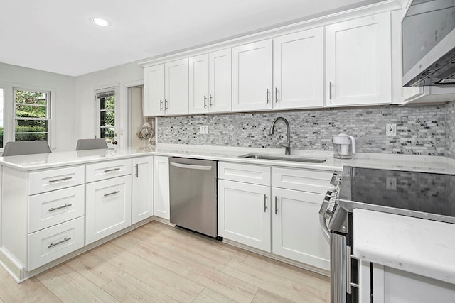 kitchen with white cabinets, appliances with stainless steel finishes, decorative backsplash, and a sink