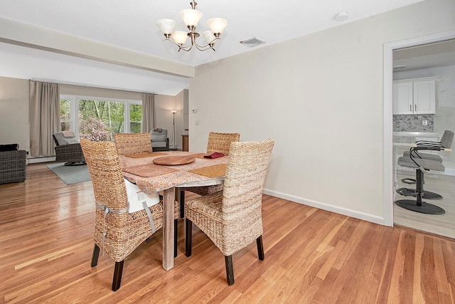 dining area with visible vents, light wood-style floors, baseboard heating, and an inviting chandelier
