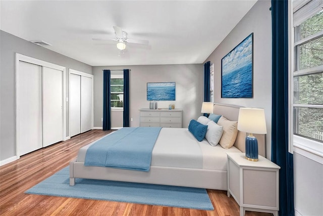 bedroom featuring visible vents, multiple closets, wood finished floors, and multiple windows