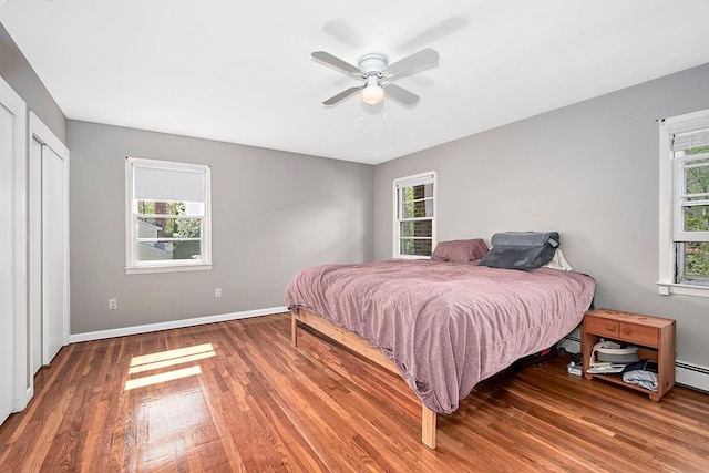 bedroom with baseboards, ceiling fan, multiple windows, and wood finished floors