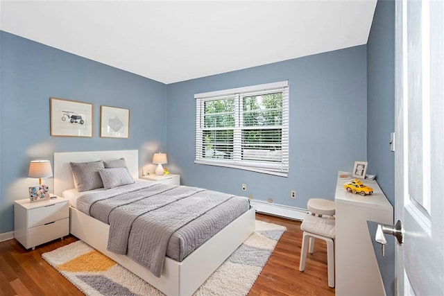 bedroom featuring baseboards, a baseboard heating unit, and wood finished floors