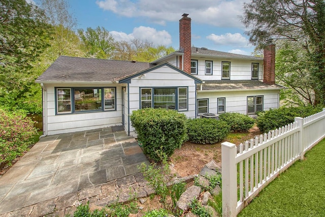 rear view of property with roof with shingles, fence, a chimney, and a patio area
