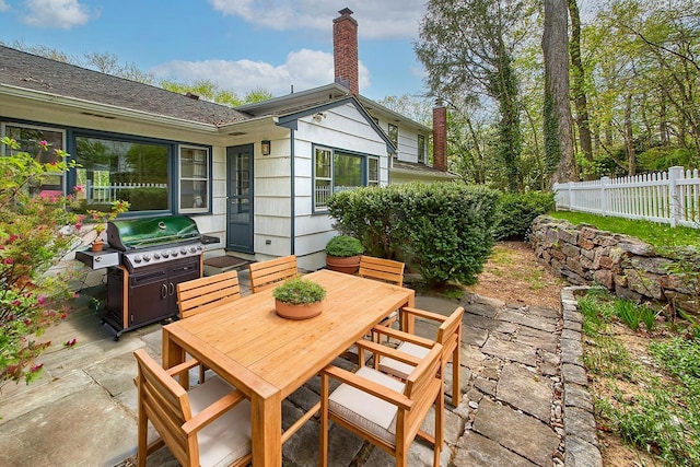 view of patio with fence, outdoor dining area, and a grill