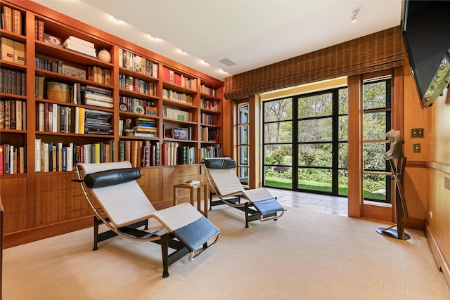 living area with visible vents, built in shelves, bookshelves, and light carpet