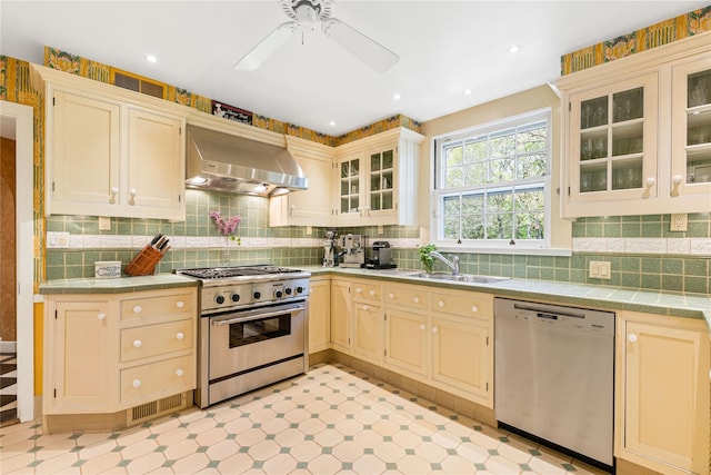 kitchen featuring a sink, ventilation hood, stainless steel appliances, and tile countertops