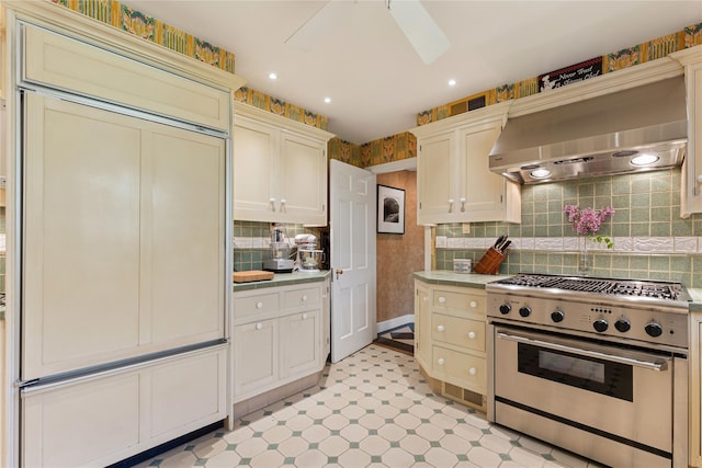 kitchen with light floors, light countertops, ventilation hood, tasteful backsplash, and high end stove