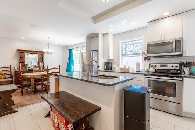 kitchen featuring a sink, dark stone countertops, backsplash, a notable chandelier, and stainless steel appliances