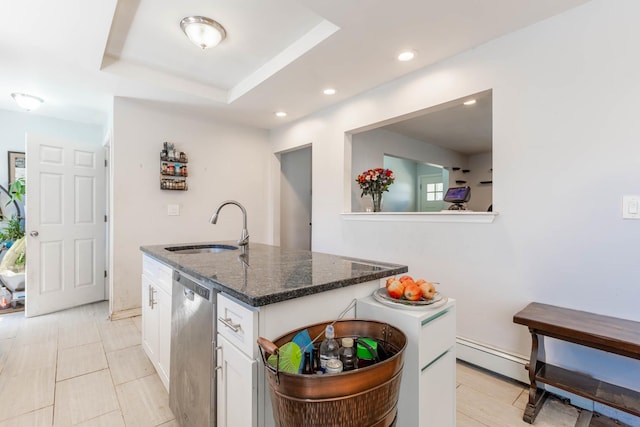 kitchen with stainless steel dishwasher, a sink, white cabinets, dark stone counters, and an island with sink