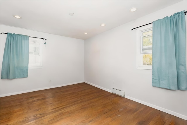 empty room featuring baseboards, baseboard heating, recessed lighting, and wood finished floors