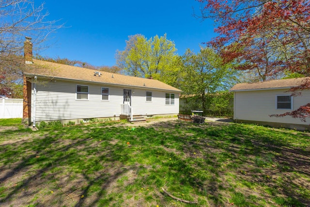 rear view of house featuring fence, a yard, and a chimney