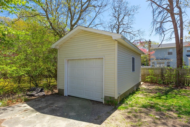 detached garage featuring fence and driveway