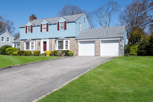 view of front facade featuring a garage, a chimney, driveway, and stone siding