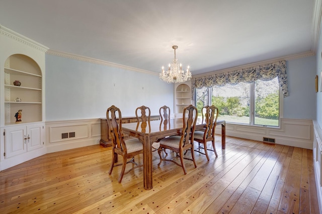 dining area featuring visible vents, light wood-style flooring, wainscoting, and built in shelves