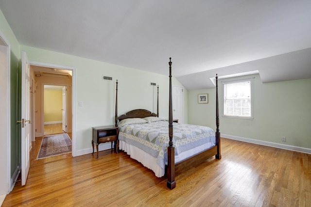 bedroom with visible vents, baseboards, vaulted ceiling, and light wood-style floors
