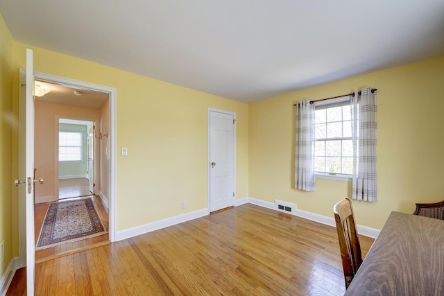 unfurnished office with wood finished floors, visible vents, and baseboards