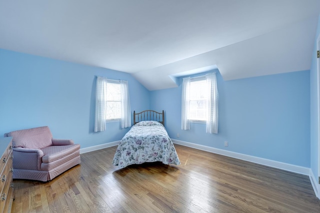 bedroom with wood finished floors, lofted ceiling, and baseboards