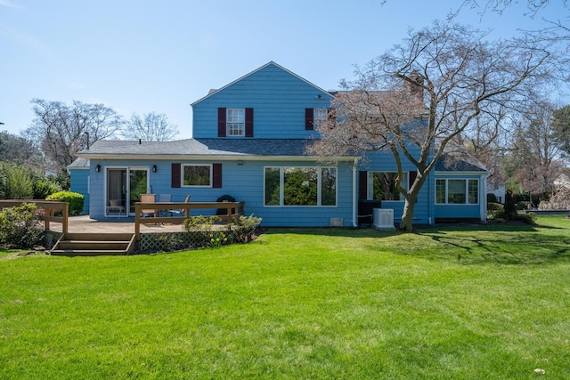rear view of property with a deck, a chimney, roof with shingles, a yard, and central AC