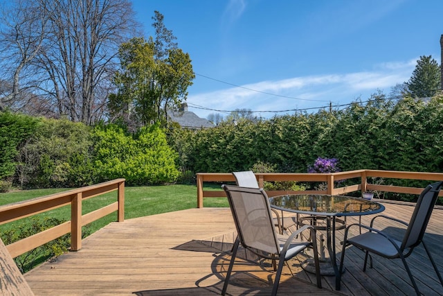 wooden terrace with a lawn and outdoor dining space