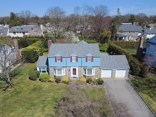 view of front of property featuring a residential view, driveway, stone siding, a front yard, and an attached garage