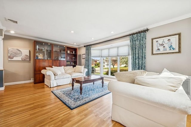 living room with baseboards, visible vents, ornamental molding, and light wood-style floors