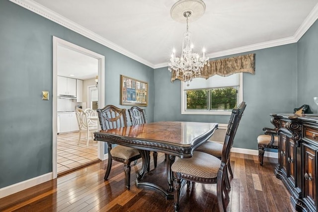dining space with crown molding, dark wood-style flooring, baseboards, and an inviting chandelier