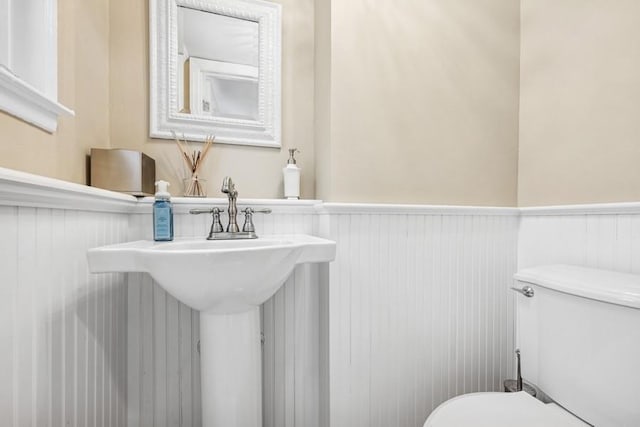 half bathroom with a wainscoted wall and toilet
