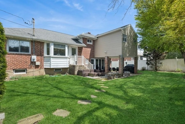 back of house featuring brick siding, a lawn, fence, and a patio