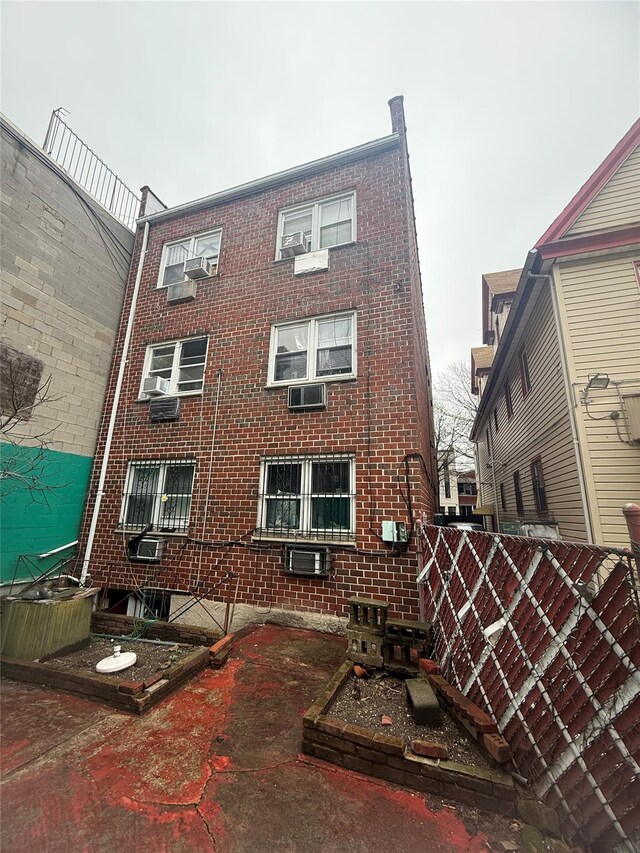 rear view of property featuring fence and brick siding